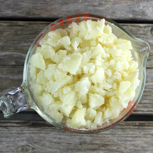 Chopped potatoes in a glass measuring cup.