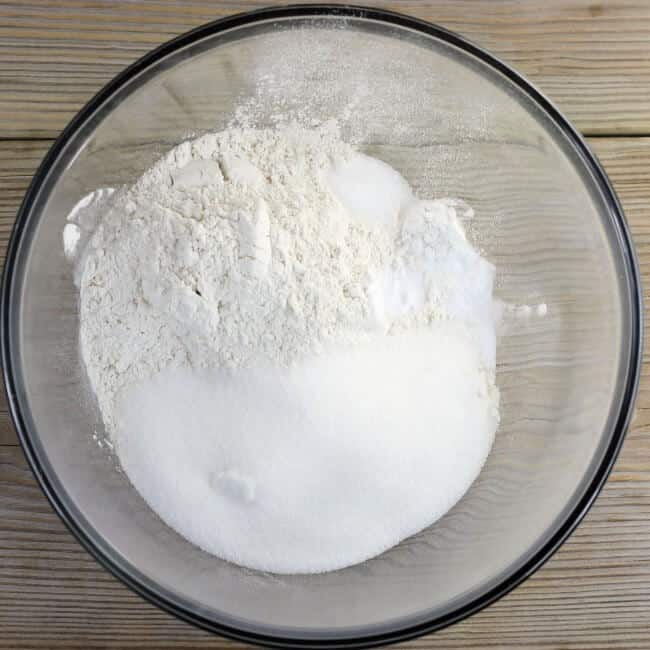 The flour, sugar, baking powder, baking soda, and salt are added to a mixing bowl.