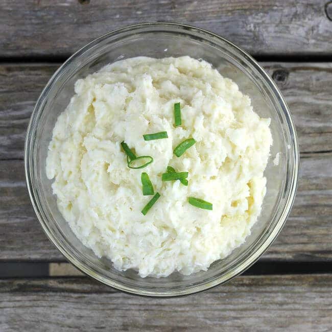 Mashed Potatoes in a bowl with slice green onions on top.