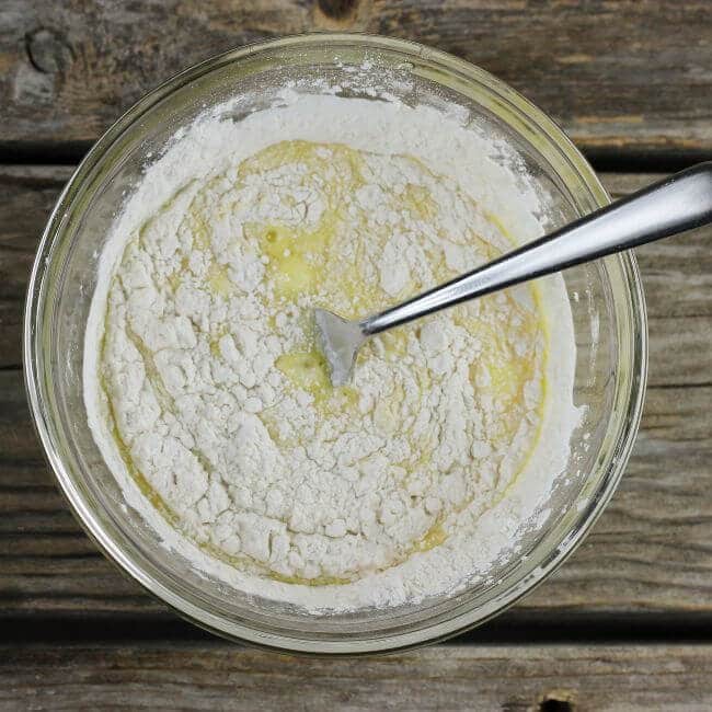 Flour is added to the egg mixture in a bowl.