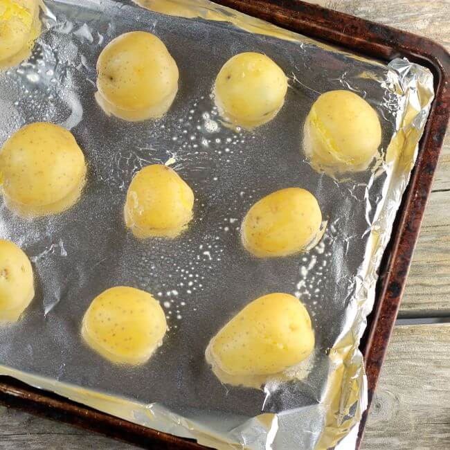 Baby potatoes on a baking pan lined with aluminum foil.
