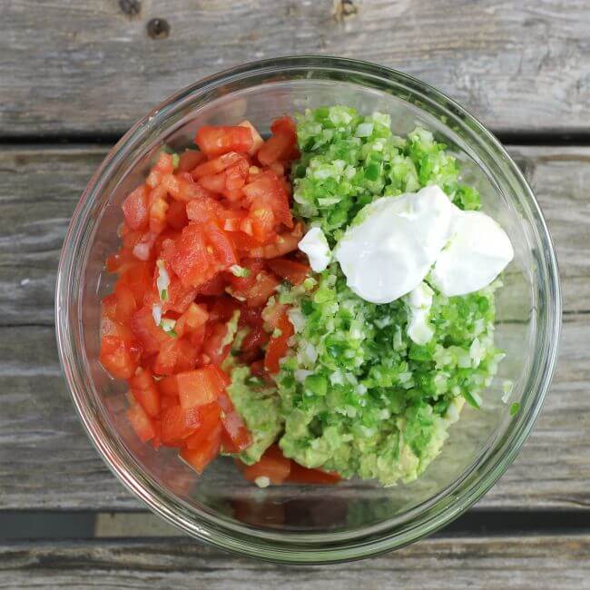Chopped vegetabes and sour cream in a glass bowl.