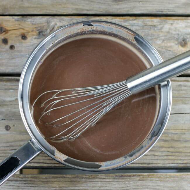Hot chocolate in a saucepan with a whisk.