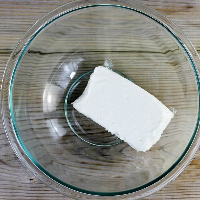A block of cream cheese in a mixing bowl.
