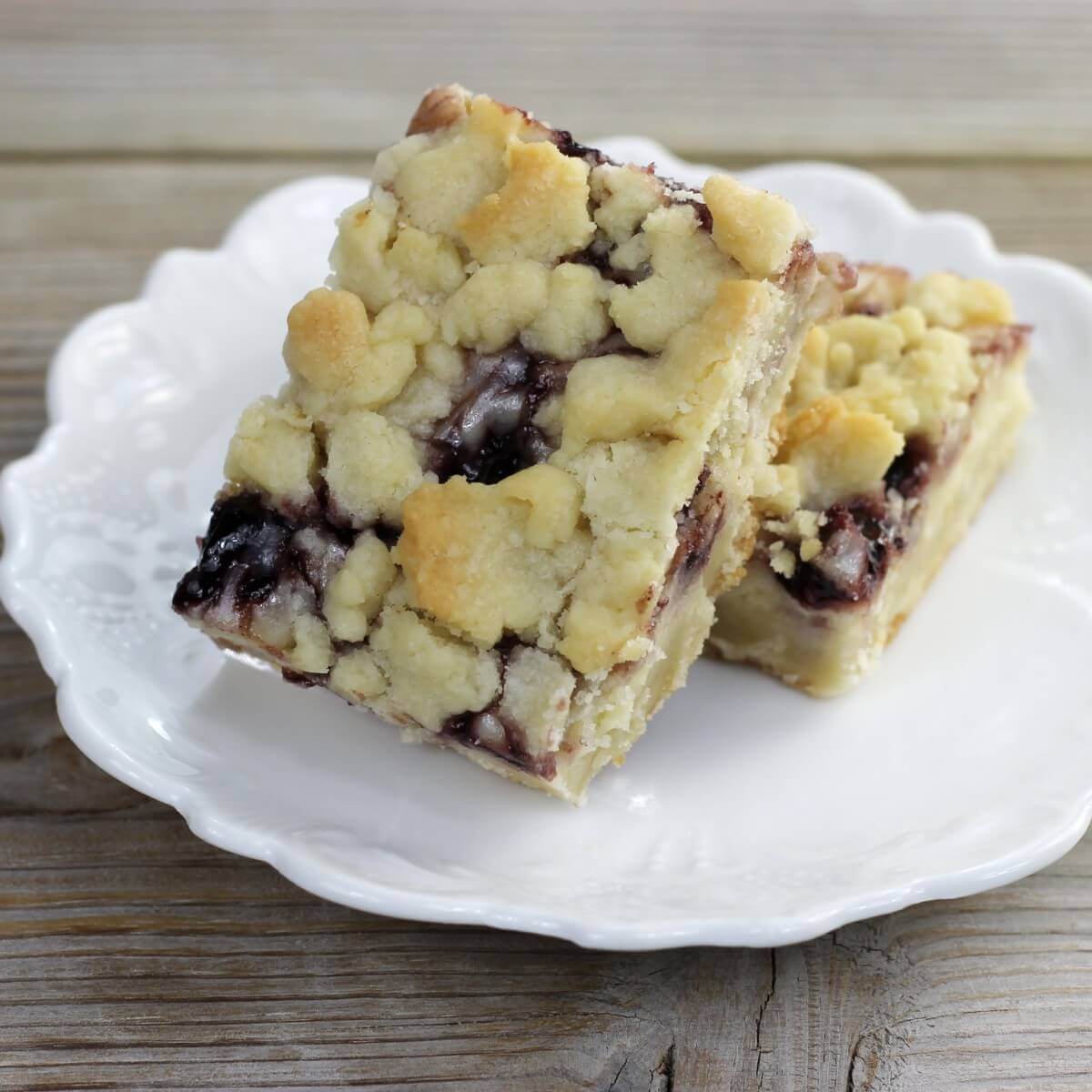 A side angle view of a plate with a couple of blackberry cream cheese shortbread bars.