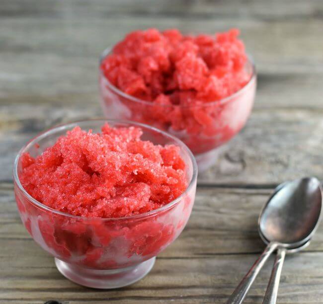 Side angle view of two bowls of Italian ice with two spoons on side.