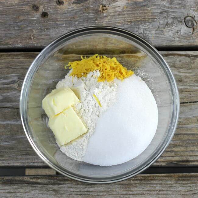 Sugar, flour, butter, and lemon zest in a glass bowl.