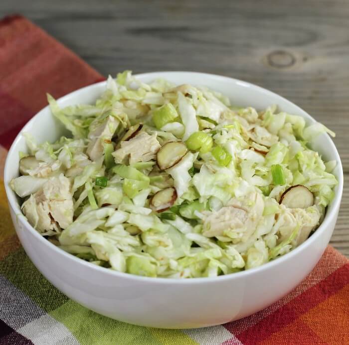 Side angle view of a cabbage salad in a white bowl.