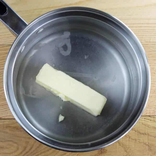 A saucepan with water and a stick of butter inside.