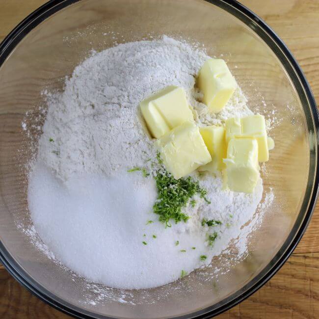 Sugar, flour, baking powder, lime zest, and butter in a bowl.