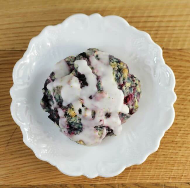 Looking down at a black raspberry scone on a white plate.