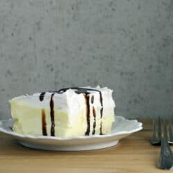Side view of a white plate with a piece of cream puff cake on it.