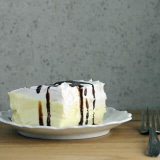 Side view of a white plate with a piece of cream puff cake on it.