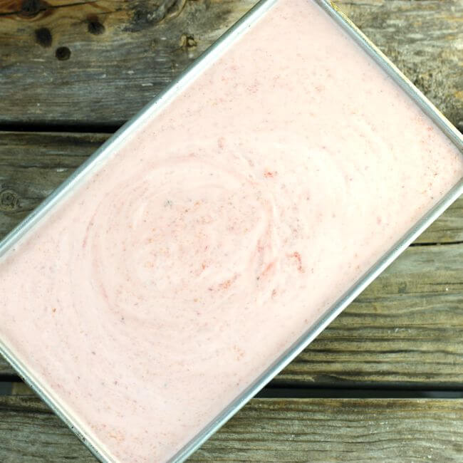 Peach strawberry yogurt is added to a loaf pan.
