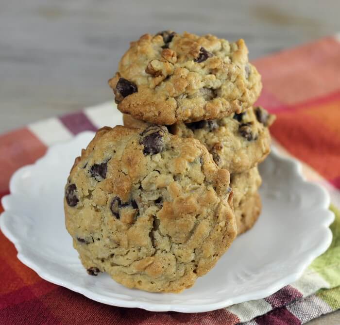 A stack of chocolate chip oatmeal walnut cookies on a white plate.