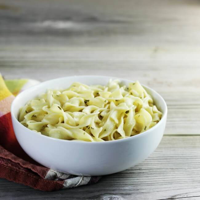 Side view of a white bowl full of noodles. 