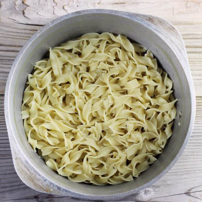 Overlooking a pot of cooked buttered egg noodles.