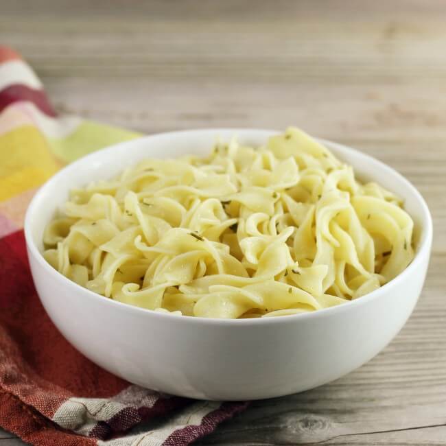 Looking at a side angle view of a bowl with buttered noodles.