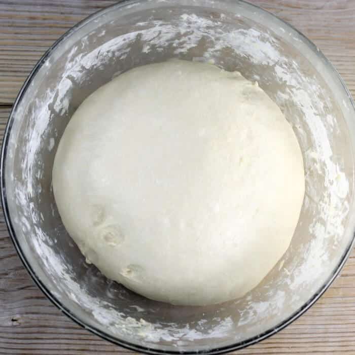 Bread dough in a large glass mixing bowl.