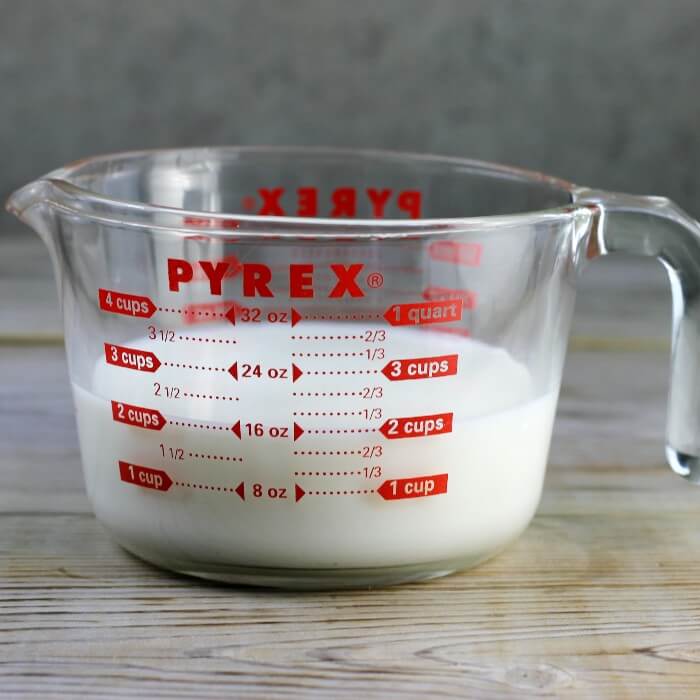 Milk and water are added to a glass measuring cup. 