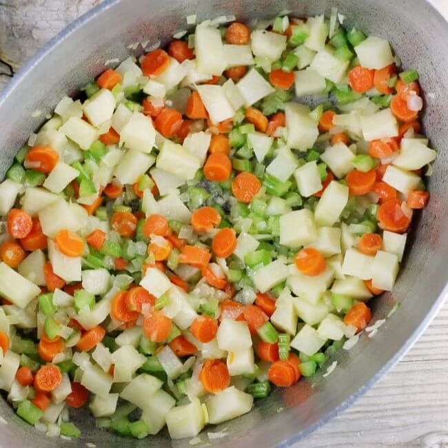 Sauteed vegetables in a soup pot.