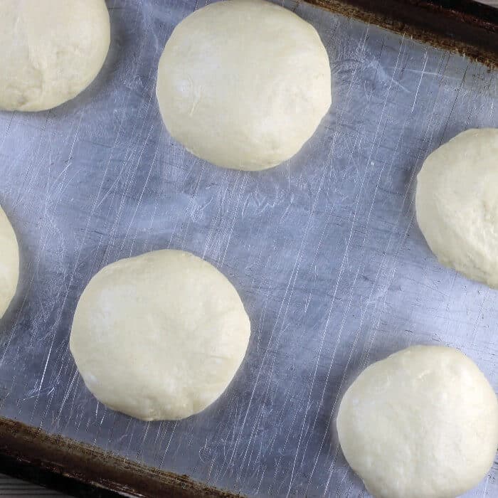 Unbaked buns are placed on a baking sheet.