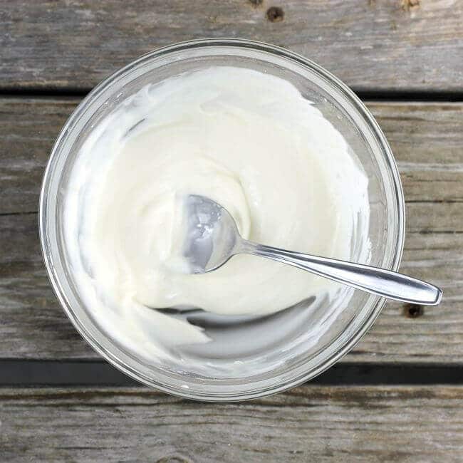 Vanilla icing in a bowl with a spoon.