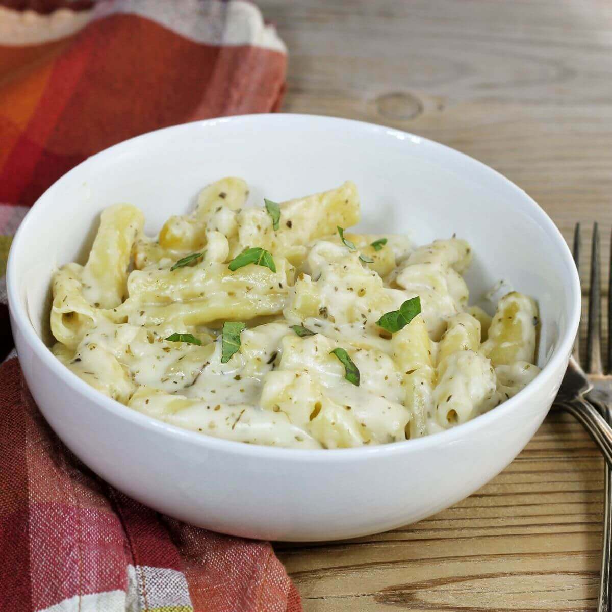 A side angle view of a white bowl with cheesy mac and cheese. 
