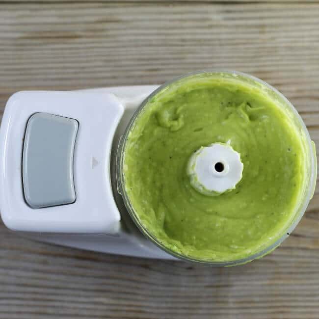 Over looking a mini food processor filled with creamy avocado dressing.
