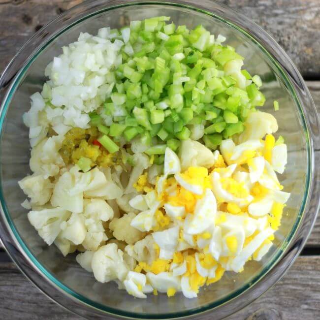 Cauliflower, chopped eggs, celery, and onion in a bowl.