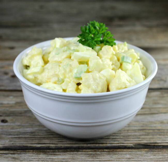 Side angle view of a white bowl with cauliflower potato salad.