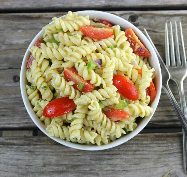 Looking down at a bowl of pasta with tomatoes and green peppers.