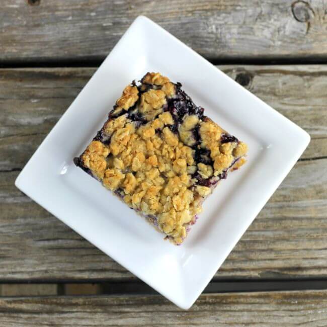 Overlooking at a blueberry crumble bar on a white plate.