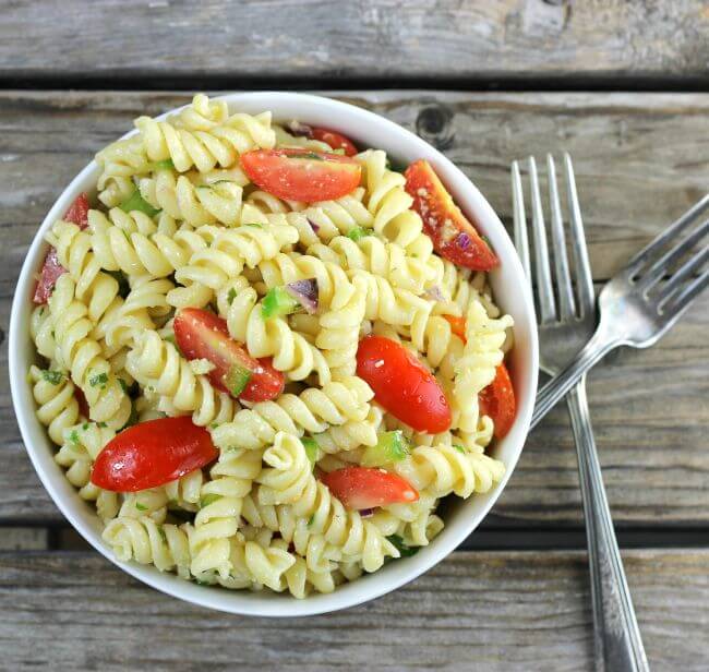 Over looking a bowl of pasta with forks on the side of the bowl.