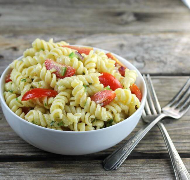 Side angle view of a bowl of pasta with two forks on the side of the bowl.