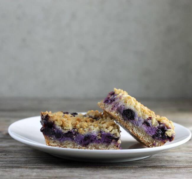 Side view of blueberry bars on a white plate.