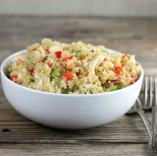 Side view of a white bowl filled with quinoa chicken salad. 