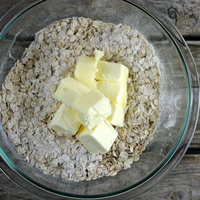 Flour, sugar, oats, and butter in a glass bowl