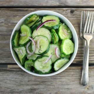 Overlooking a white bowl of cucumber salad.