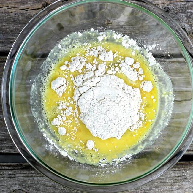 Adding flour to egg mixture in a glass bowl.