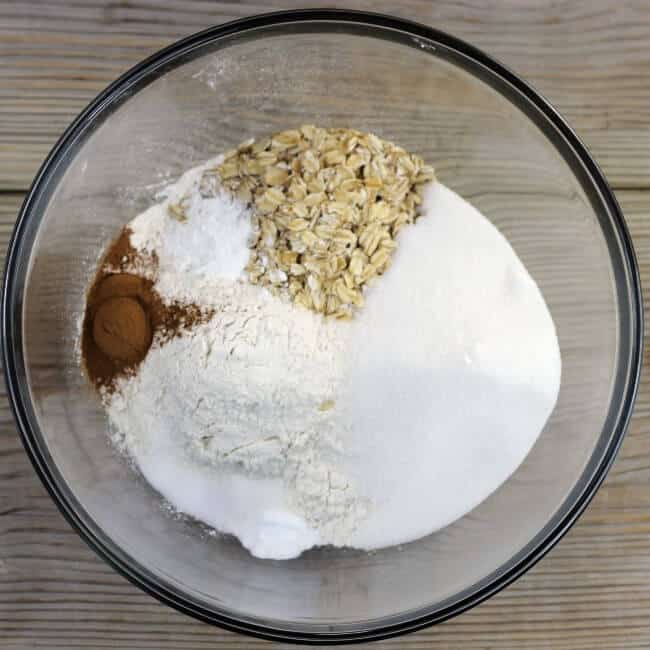 Sugar, flour, oats, cinnamon, baking powder, baking soda, and salt are added to a large mixing bowl.