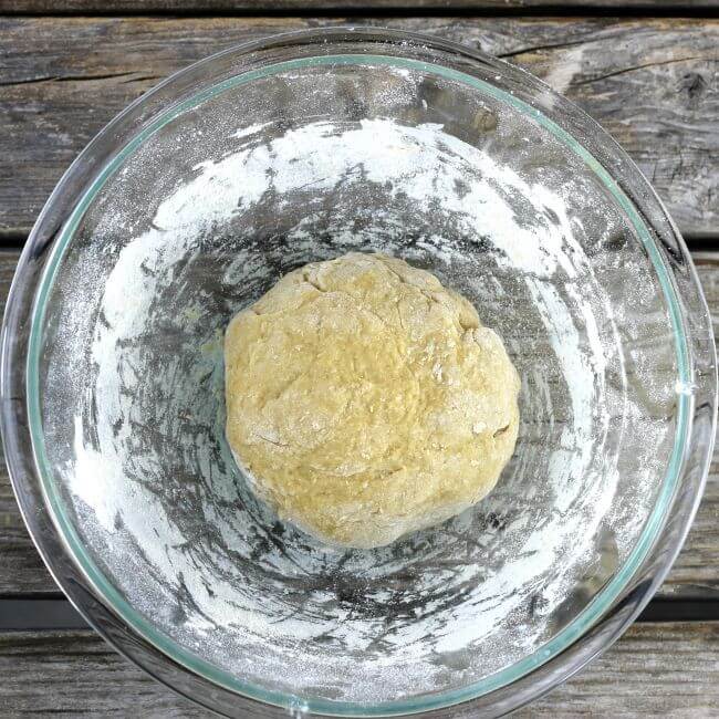 A ball of noodle dough in a glass bowl.