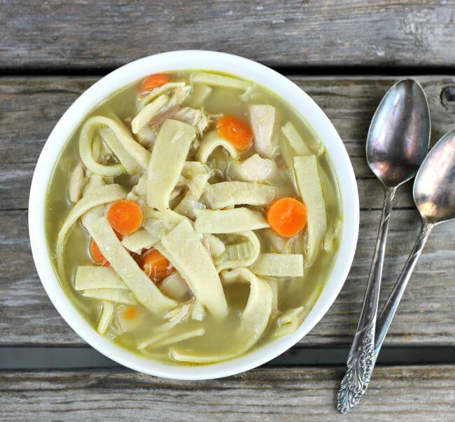 Overhead view of chicken noodles soup in a white bowl.