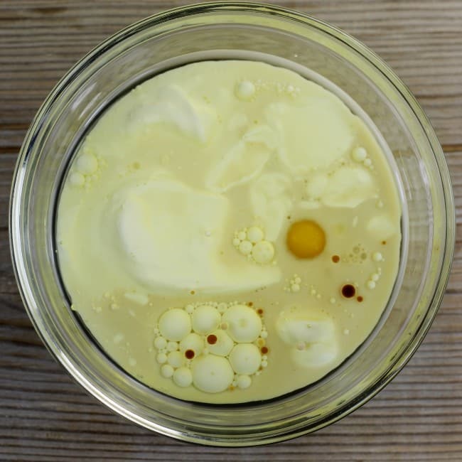 The egg, milk, sour cream, oil, and vanilla are added to a small bowl.
