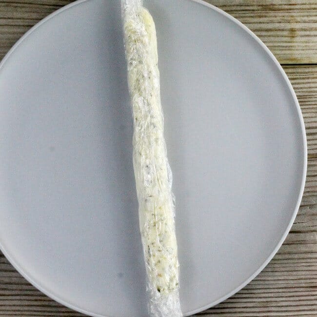 A roll of butter in plastic wrap on a gray plate.