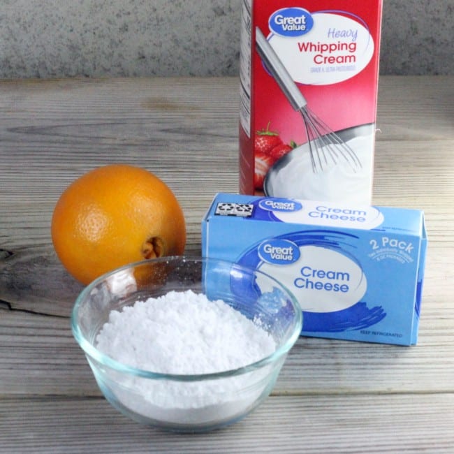 An orange, a bowl of powdered sugar, cream cheese, and cream.