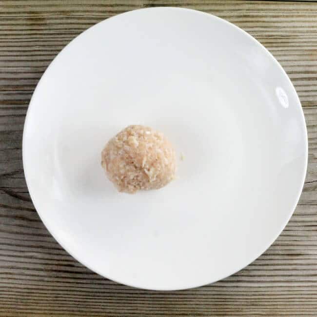 Looking down at a meatball on a white plate.