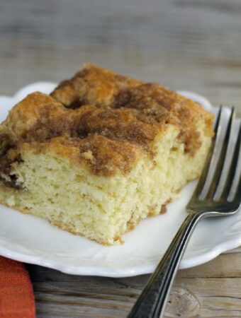 A side angle view of a slice of quick sour cream coffee cake on a white plate.