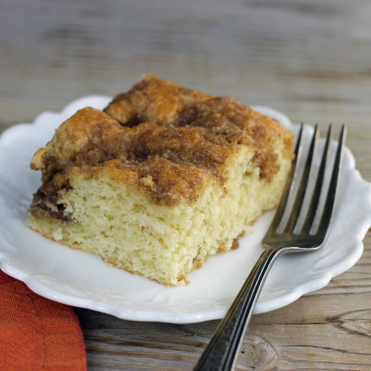 A side angle view of a slice of quick sour cream coffee cake on a white plate. 