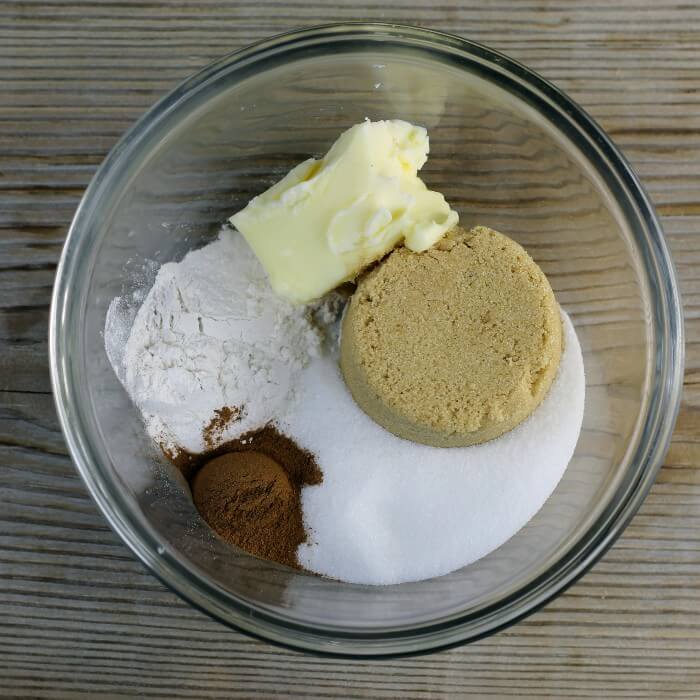 Sugar, brown sugar, flour, cinnamon, and butter are added to a small bowl.